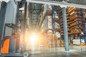 Large modern industrial logistic warehouse with forklifts, sunlight