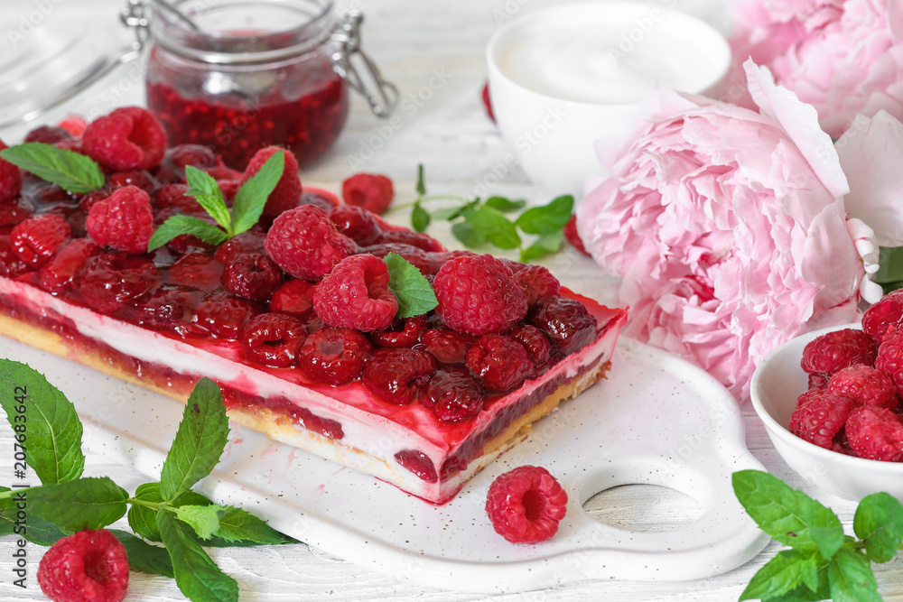 Wall mural raspberry creamy cake or cheesecake with freash berries, mint, jam, peony flowers and cup of cappucc