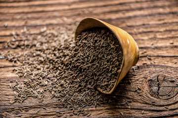 loose cumin seeds in a small wooden dish o a table