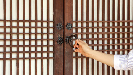 The woman's hand at opening the door to the Korean traditional house.