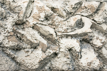 Close up of a rough textured plaster wall coating, imitation of stone masonry. Abstract grey patchy background.