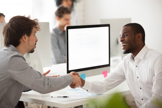 Smiling Worker Shaking Hand Of Caucasian Client, Greeting, Making Good First Impression, Black Employer Congratulating Job Applicant With Successful Interview, Handshaking. Mock Up Computer  Screen