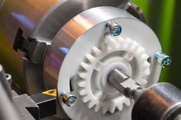Working on a lathe with a tool bit and a workpiece. Close-up of the machine-tool when turning a plastic cylinder with an aluminum surface. Metal cutting tool with a sharp yellow tip. © KPixMining