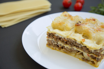 Lasagne on a white plate, dark background, side view.