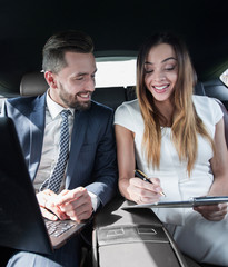 man and woman discussing work documents in taxi