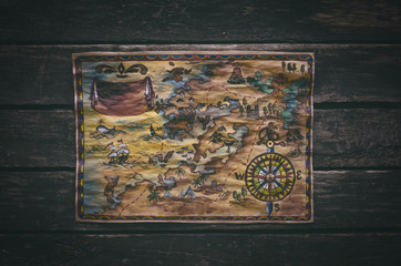 Pirate treasure map with gold mark on aged wooden table background. Top view photo.