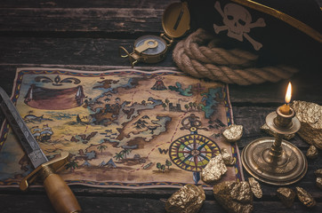 Pirate treasure map, gold nuggets, dagger and pirate hat on aged wooden table background. Sea...