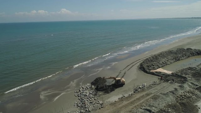 Construction of coastal protective structures, construction of structures to protect against sea waves on Lingayen Beach. Aerial view construction equipment at sea, beach facilities, construction of