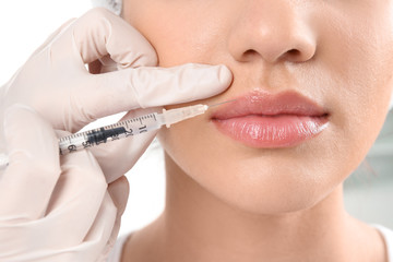 Young woman getting lip injection in beautician salon, closeup