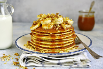 Homemade hot banana pancakes with caramel sauce and nuts.