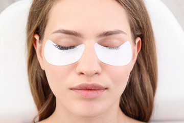 Young woman undergoing eyelash extensions procedure, closeup