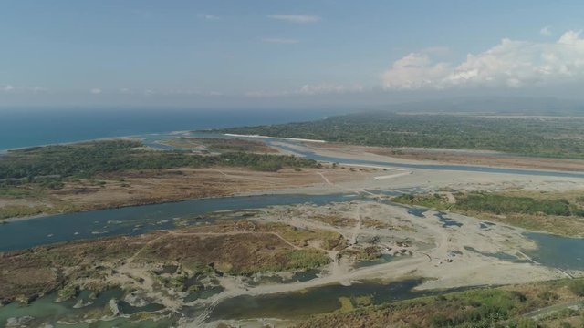 Aerial view of rver flowing into the sea in Philippines,Luzon. ropical landscape with sandy coast and river among farmer fields flowing into the blue ocean