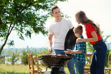 Naklejka na ściany i meble Happy family having barbecue with modern grill outdoors