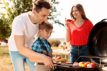 Happy family having barbecue with modern grill outdoors
