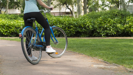 Girl rides bicycle in a city park close up