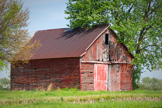 An abandoned farm barn sits in a weathered state as it deteriorate over time