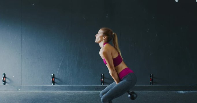 Beautiful athletic woman exercising with kettlebell in the gym