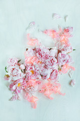 Beautiful pink, rose peonies decorated on white wood table with funny flamingo chain of lights, can...