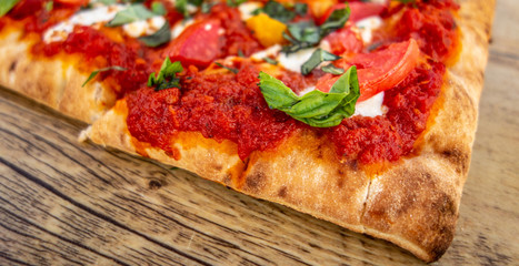 Slice of Classic Margherita Flatbread: Tomato Base, Fresh Mozzarella, Sliced Tomatoes, Basil on old rustic wood board, close up, wide photo