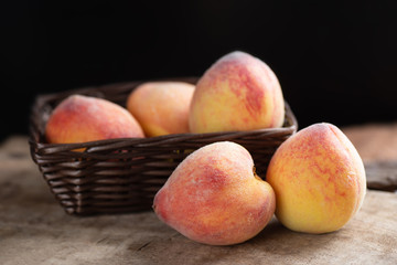 Ripe peaches in a basket on wooden, tropical fruit