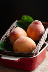 Ripe peaches in a basket and bowl on wooden, tropical fruit