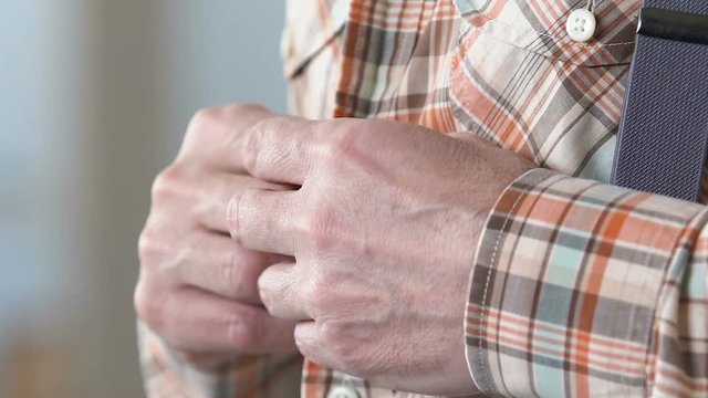 Old man buttoning up plaid shirt, morning ritual, preparing for date, clothes