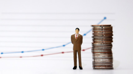 A pile of miniature man and coins stands in front of a linear graph....
