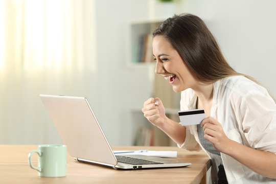 Excited woman paying online at home