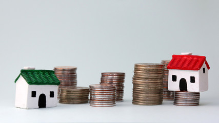 A miniature house on a pile of different heights of coins....