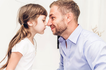 Little girl with dad smiling and touching nose together at home.Love of family and father day concept