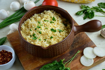 Bulgur in plate on wooden table. Traditional middle eastern or arab dish. Top view. vegetarian dinner. Bulgur  with vegetables, spices on white background. Flat la