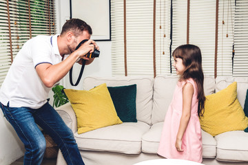 Father making photo his little daughter at home