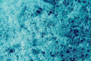 Close up of a lot of blue suds on water.