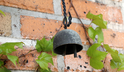 Metallic wind-bell on the red brick wall.