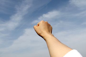 A woman's hand clenched her fist against the blue sky.