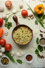 Bulgur in plate on wooden table. Traditional middle eastern or arab dish. Top view. vegetarian dinner. Bulgur  with vegetables, spices on white background. Flat la