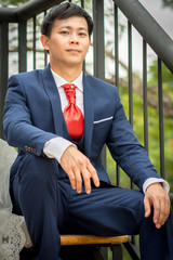 Man wearing dress sitting on the stairs to enjoy.