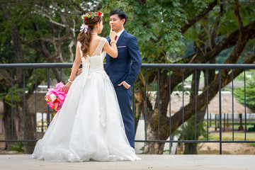 The bride carries a bouquet of flowers and hands on the groom's mouth.