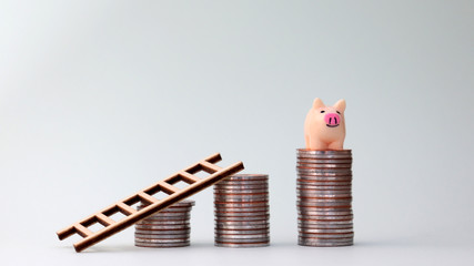 Small piggy bank and ladder on top of the pile of coins. Cost creation concept.
