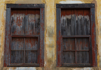 Old wooden windows, worn by the action of time, the colors yellow and red faded. Located in the State of Minas Gerais, Brazil.