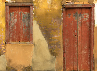 Door and window of an old house, red and yellow tones worn by time, a magnificent color contrast.