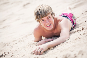 Smiling teen laying in the sand on a dune at the beach
