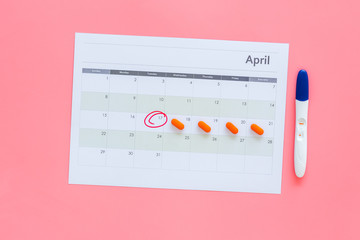 Planning pregnancy. Positive pregnancy test near calendar page and pills on pink background top view copy space