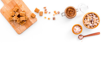Cook caramel sauce. Melted caramel in glass jar, caramel cubes on cutting board, sugar and salt on...