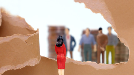 Torn paper and miniature people. Discriminatory view of women in the company.