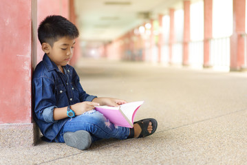 asian children holding book in hand and sitting read a book within school.education and people...