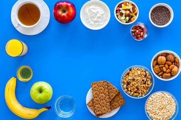 Make a menu for wholesome breakfast. Fruits, oatmeal, yogurt, nuts, crispbreads, chia on blue background top view copy space