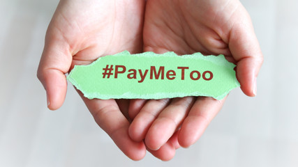 #PayMeToo as a new social movement. A piece of paper with #PayMeToo written on the palm of a woman's hand.