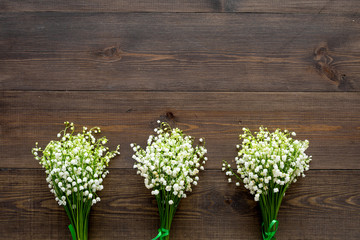 May flowers. Bouqet of lily of the valley flowers on dark wooden background top view copy space