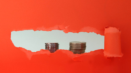 A pile of two coins visible behind the red torn paper.